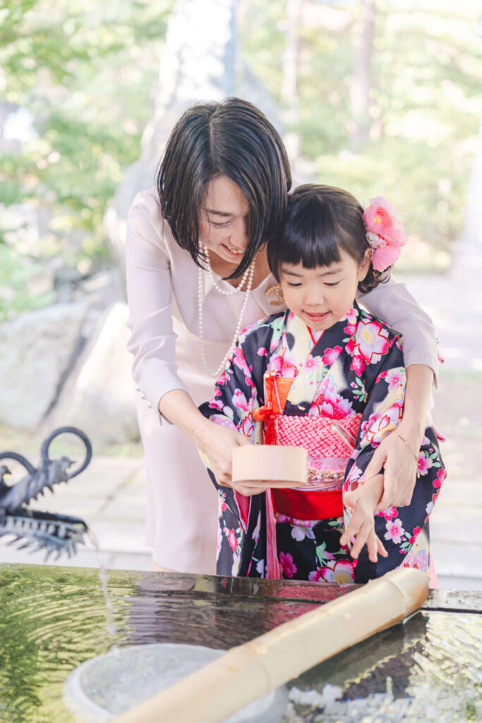 札幌護国神社の手水舎でお母さんと一緒に手を清める七五三の女の子